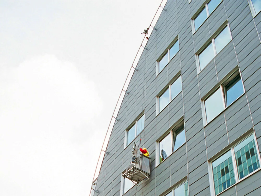 Suspended access cradle working on a glass facade